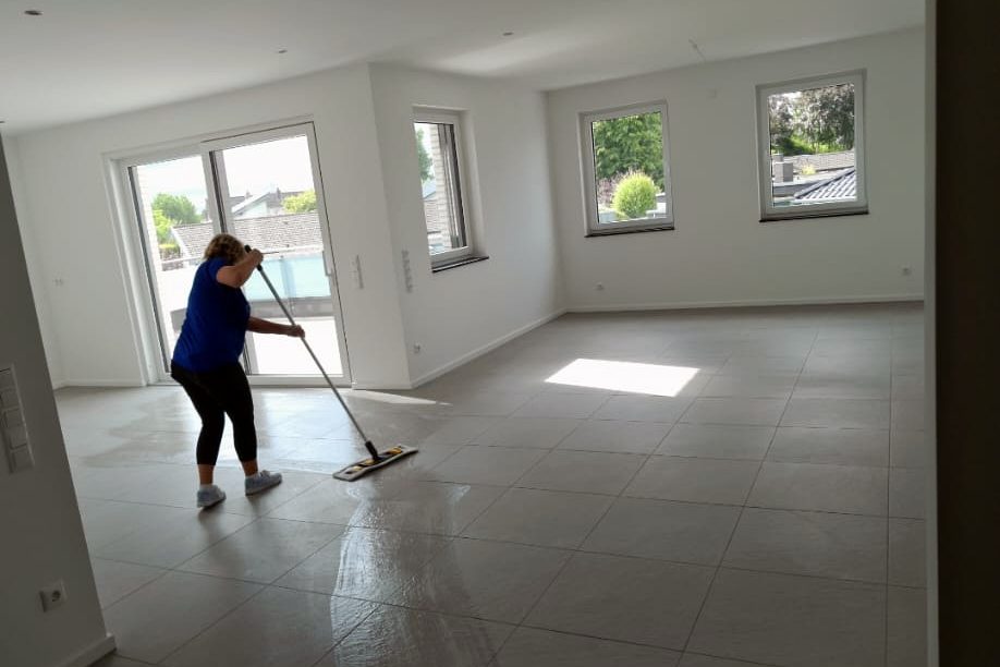 Bauendreinigung: Wischen einer großen Fliesenfläche in einem Neubau