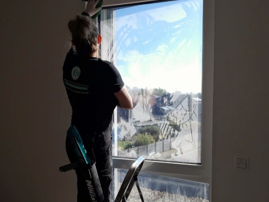 Fensterreinigung einer großen Fensterfront mit Abzieher und Leiter